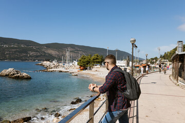 Fototapeta na wymiar Man on the Promenade looks at yachts in well-preserved medieval town Herceg Novi near Bay of Kotor, the Adriatic Sea in southwestern Montenegro. Travelling and leasure concept. Recreation area