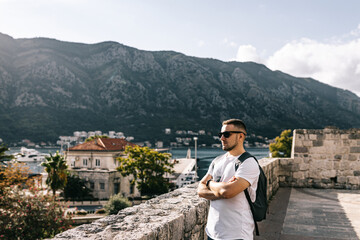 Fototapeta na wymiar Man stands on Kotor old wall Fortification in Montenegro. Unesco world heritage. Europe travel site. Vacation concept. Tourism in adriatic sea. Serbian history of balkans, fort and port buildings..