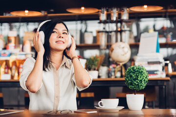 Lifestyle freelance woman he using earphones listening music during working on laptop computer in coffee shop