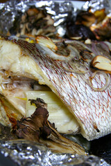 Grilling red seabream with mushroom and garlic on the aluminum foil....