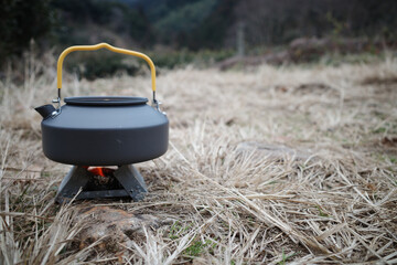 野に置かれたポケットストーブとケトル