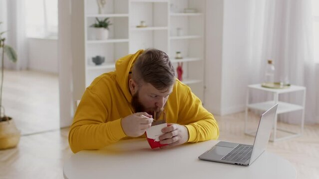 Male Freelancer Eating Noodles Near Computer Having Lunch At Home