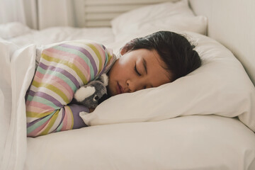 Young mixed race Asian girl sleeping in bed with her soft toy, good night sleep, bedtime routine, wake up kid for school, children sleep disorder, unwell concept