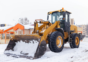 Big orange tractor cleans up snow from the road and loads it into the truck. Cleaning and cleaning...