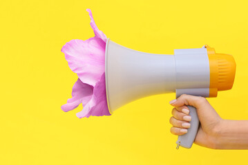 Woman with megaphone and gladiolus flower on yellow background