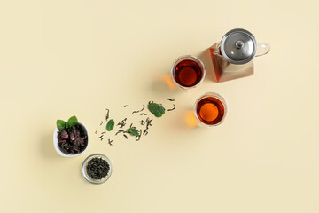 Composition of teapot and glass with tasty tea on yellow background