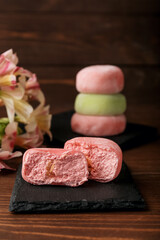 Board with delicious mochi and flowers on table