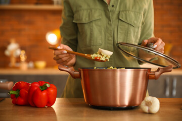 Woman preparing pilaf in cooking pot