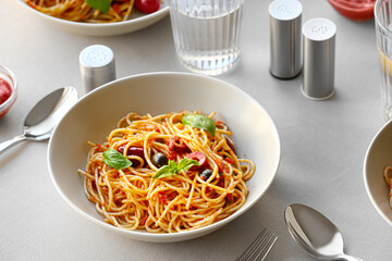 Plate of tasty Pasta Puttanesca on table in restaurant