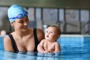 Female coach and adorable little baby in swimming pool
