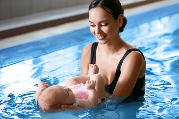 Young woman with her little baby in swimming pool