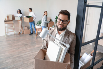 Handsome man holding box with personal things in office on moving day