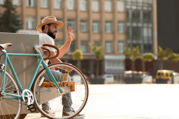 Handsome bearded man with bicycle waving hand on city square