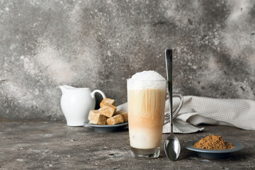 Glass of tasty iced hojicha latte and powder on grey background