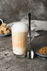 Glass of tasty hojicha latte and powder on grey background