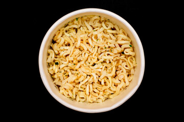 Instant Noodles in Disposable Cup on Black Background - Top View. Asian Fast Food. Quick Lunch