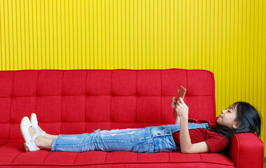 Studio shot of Asian young preschooler daughter girl in denim jeans overalls outfit laying down...