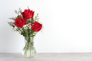 Valentine’s day concept, Red roses flower bouquet in glass vase on table background with copy...