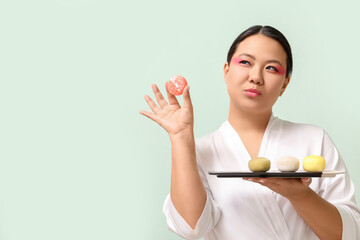 Beautiful Asian woman with tasty Japanese mochi on color background