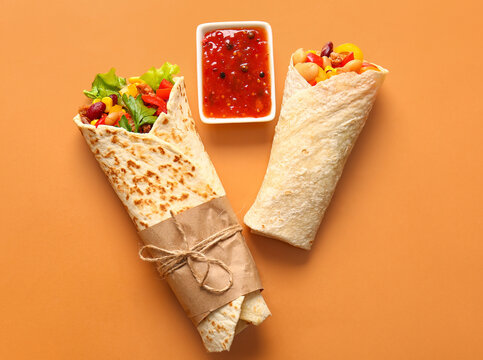 Delicious burritos and sauce on color background