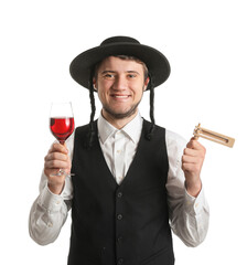 Young Jewish man with glass of wine and gragger for Purim holiday on white background