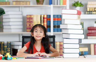 Asian creative young primary school girl artist in casual outfit sitting using color pencil drawing painting picture at home school classroom lesson in living room during pandemic quarantine period