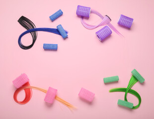 Colorful hair strands with curlers on pink background
