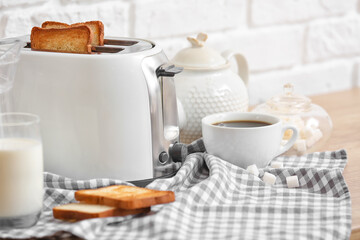 White toaster with bread slices and drinks on table near brick wall