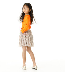 Full body cutout isolated studio shot of Asian young primary schoolgirl model in casual orange shirt and skirt outfit standing on white background