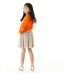 Full body cutout isolated studio shot of Asian young primary schoolgirl model in casual orange shirt and skirt outfit standing on white background