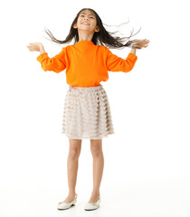 Full body cutout isolated studio shot of Asian young primary schoolgirl model in casual orange shirt and skirt outfit standing holding hand spreading long hair blowing with wind on white background