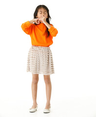 Full body cutout isolated studio shot of Asian young primary schoolgirl model in casual orange shirt and skirt outfit standing on white background