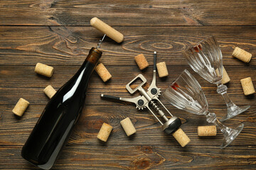 Bottle of wine, openers, corks and glasses on wooden background