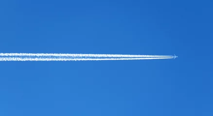Fensteraufkleber Flugzeug Der Blick auf die Kondensstreifen des Flugzeugs am blauen Himmel.