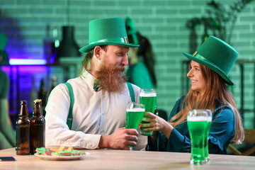 Young couple with glasses of beer celebrating St. Patrick's Day in pub