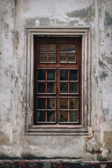 Fototapeta na wymiar Vintage brown wooden window with square glasses. Cracked wall plaster.