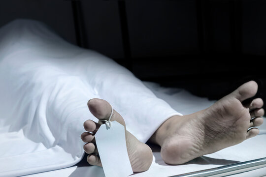 Human corpse covered with a sheet and name tag on toe
