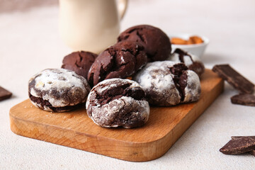 Wooden board of chocolate brownie cookies on light background