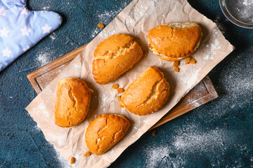 Wooden board of tasty sochniki with cottage cheese on dark background