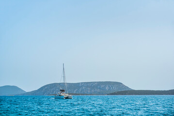 Catamaran sailing boat in the Aegean Sea under the clear blue sky on a sailing vacation,...