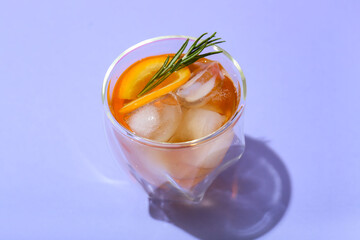 Glass of delicious Old Fashioned Cocktail on purple background