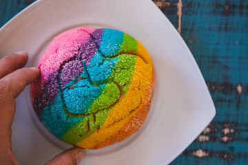 Colorful Rainbow Concha Mexican Pastry on a white plate. A sweet bread with a Heart Shape for LGBT Valentines - a symbol of queer love.
