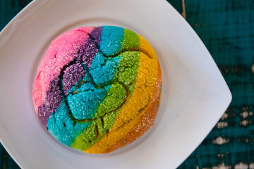 Colorful Rainbow Concha Mexican Pastry on a white plate. A sweet bread with a Heart Shape for LGBT Valentines - a symbol of queer love.