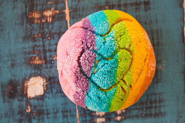 Colorful Rainbow Concha Mexican Pastry on a blue wooden table. A sweet bread with a Heart Shape for...