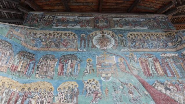 Detail Of Murals In Blue Exterior Walls Of Voronet Monastery In Suceava, Romania. Tilt-down Shot 