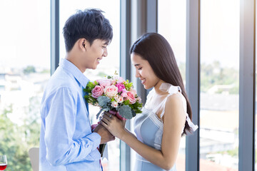 Valentine's day concept,asian Young happy sweet couple holding bouquet of red and pink roses After lunch In a restaurant background,Love story couple