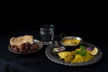 Chicken Biryani, traditional spicy Muslim food, yellow rice cooked with aromatic spices with chicken, food after the fasting month of Ramadan ends with water and dates, Muslim food style
