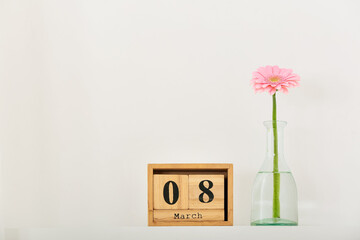 Calendar and vase with flower for International Women's Day celebration on light background