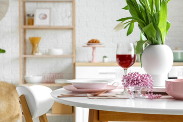 Dining table with setting and glass of wine for International Women's Day celebration in kitchen