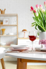 Dining table with setting and glass of wine for International Women's Day celebration in kitchen